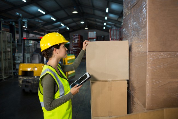 Une femme avec une tablette à la main qui s'apprête à scanner les cartons Une femme avec une tablette à la main qui s'apprête à scanner les cartons